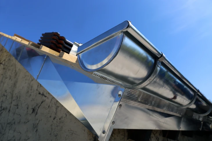 Scène extérieure montrant l'évacuation d'eau pluviale d'un bâtiment par gouttière en PVC blanc