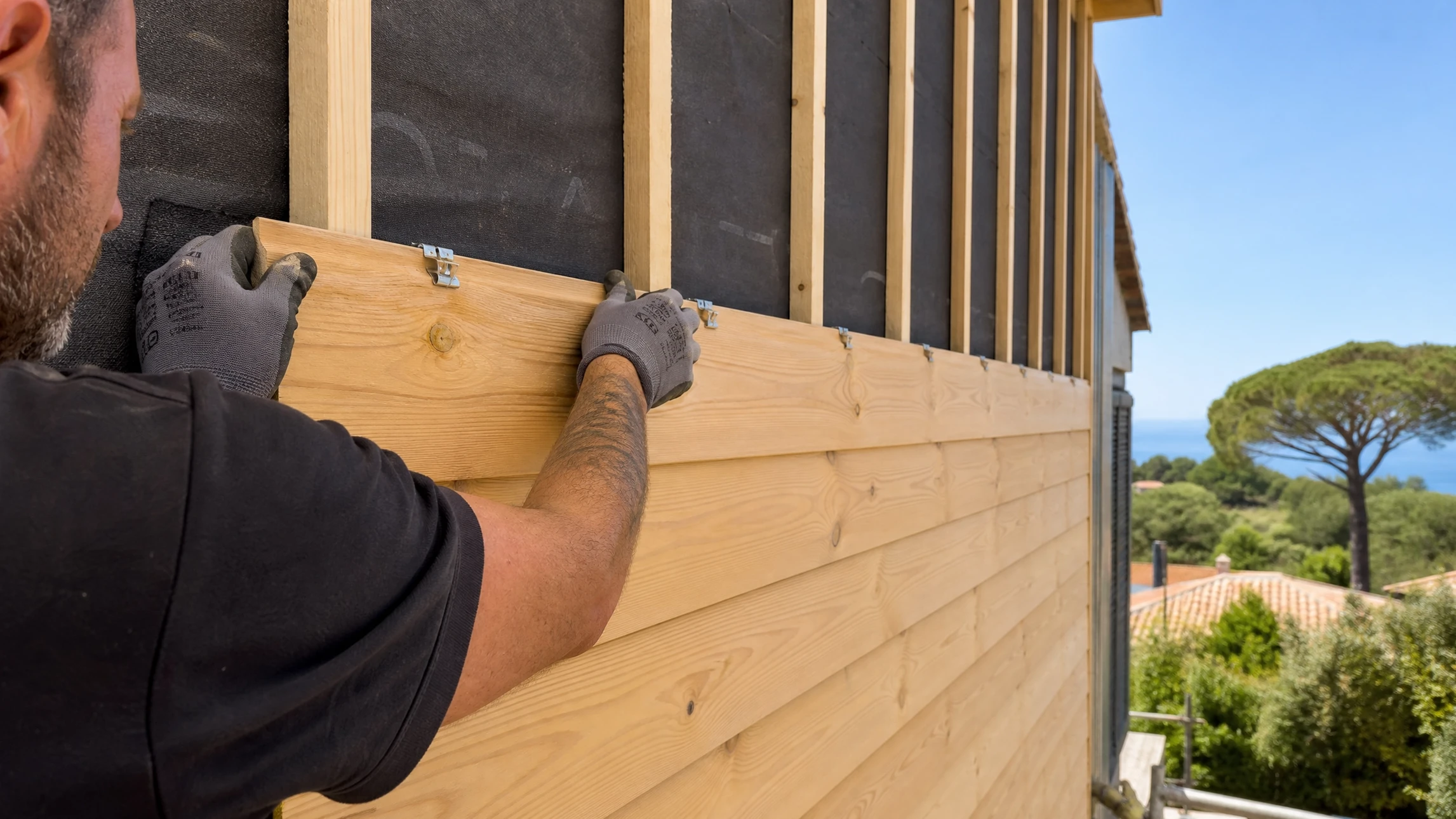 Chantier extérieur de construction d'une terrasse en bois devant maison résidentielle à bardage jaune